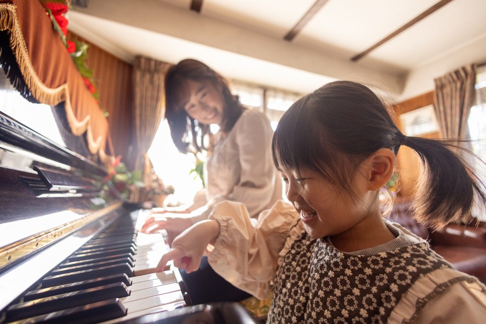 媽媽笑著陪女兒一起坐在鋼琴前練琴、孩子開心地按下琴鍵——家長的日常陪伴讓重來保持好玩